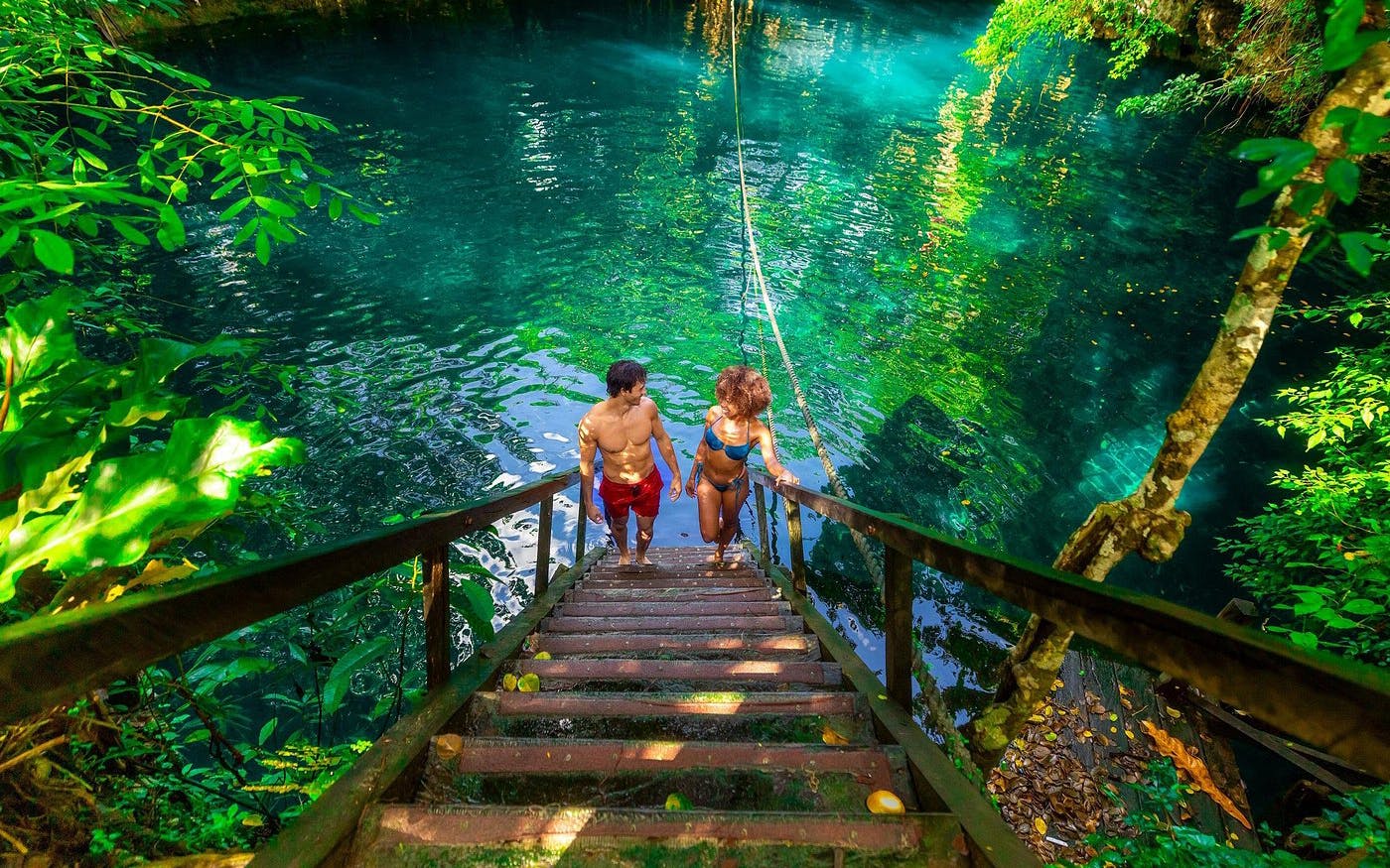 Visitors descending stairs into a cenote during a Cancun jungle adventure.