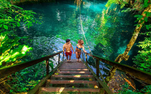 Visitors descending stairs into a cenote during a Cancun jungle adventure.