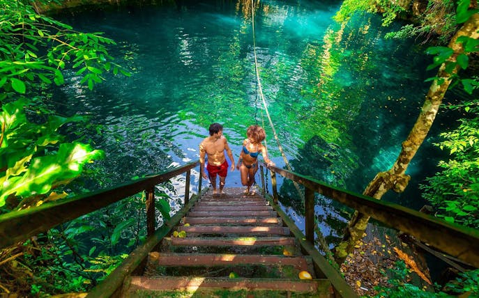 Visitors descending stairs into a cenote during a Cancun jungle adventure.