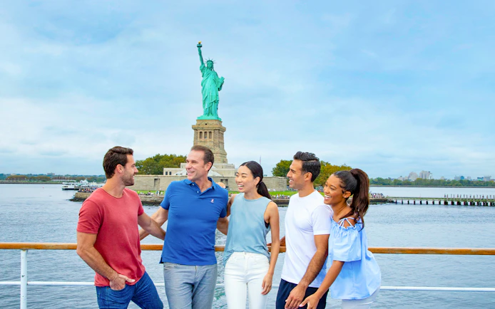 Friends enjoying New York Signature Lunch Cruise with Statue of Liberty in background.