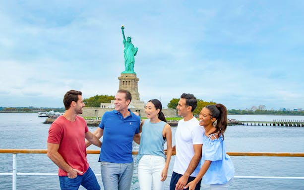 Friends enjoying New York Signature Lunch Cruise with Statue of Liberty in background.