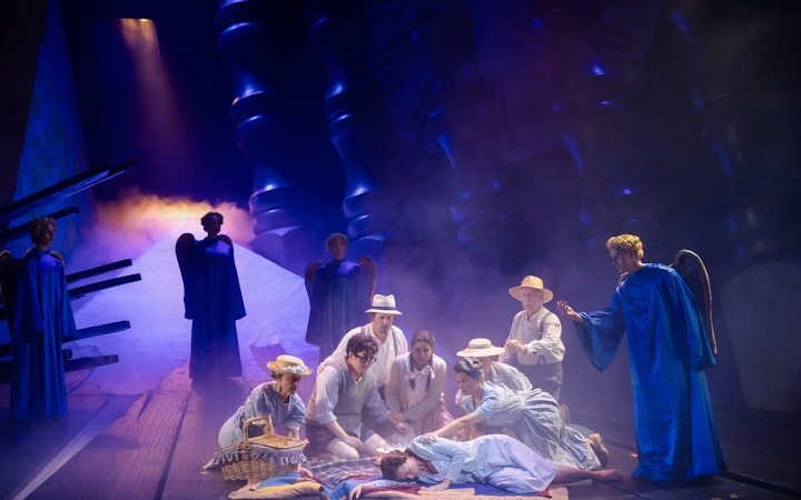 Stage performance of Hansel and Gretel with actors in period costumes and angel figures.