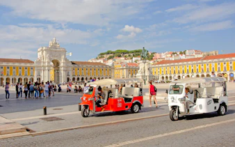 Electric tuk tuks in Lisbon's Praça do Comércio with Arco da Rua Augusta in the background.