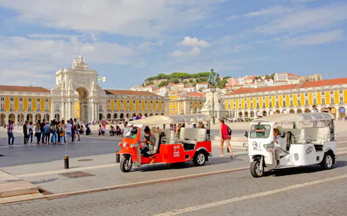 Electric tuk tuks in Lisbon's Praça do Comércio with Arco da Rua Augusta in the background.