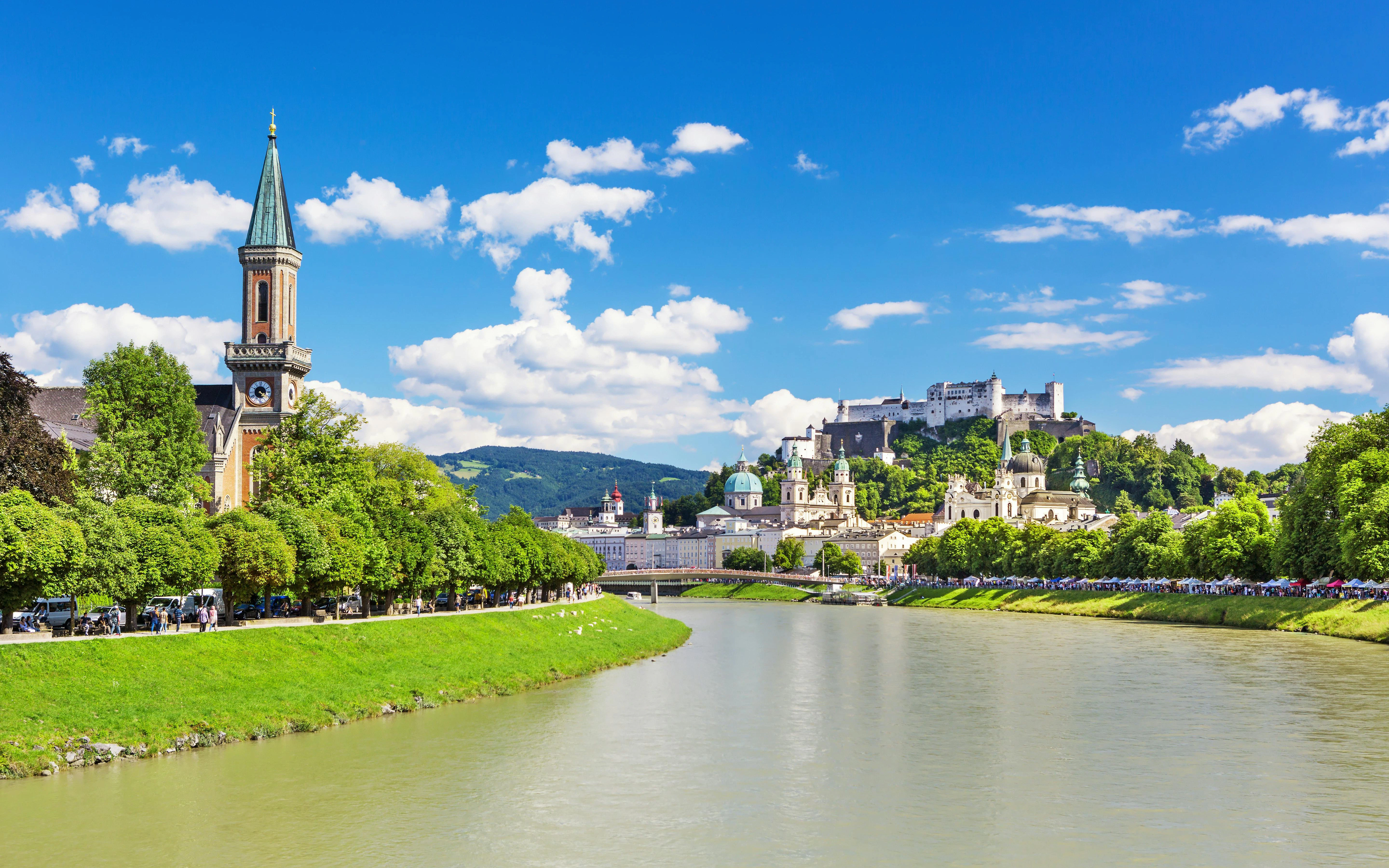 River view of Salzburg with Hohensalzburg Fortress and historic architecture, Austria.