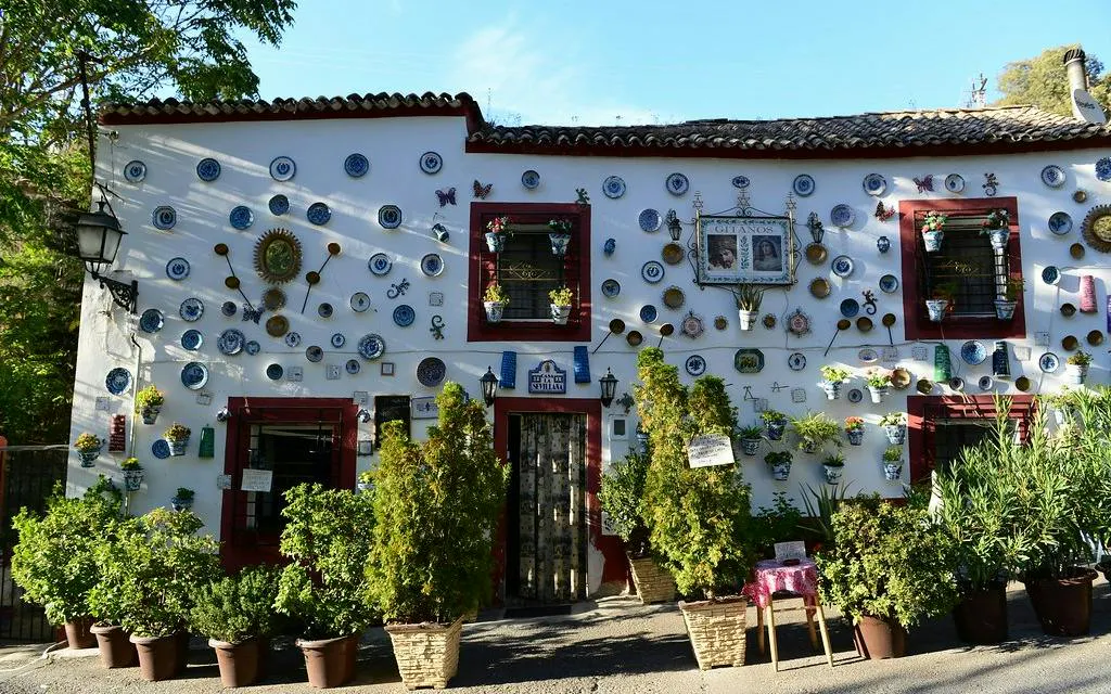 Facade of a house in Sacromonte, Granada, adorned with decorative plates and plants.