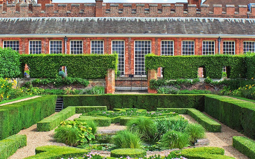 Hampton Court Palace garden with intricate hedges and flowers, Magic Gardens tour.