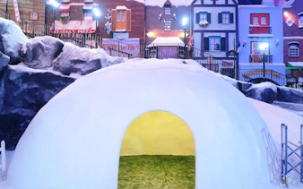 Igloo structure at Genting Highlands Snow World Theme Park with colorful village backdrop.