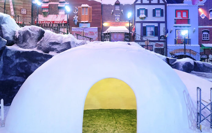 Igloo structure at Genting Highlands Snow World Theme Park with colorful village backdrop.