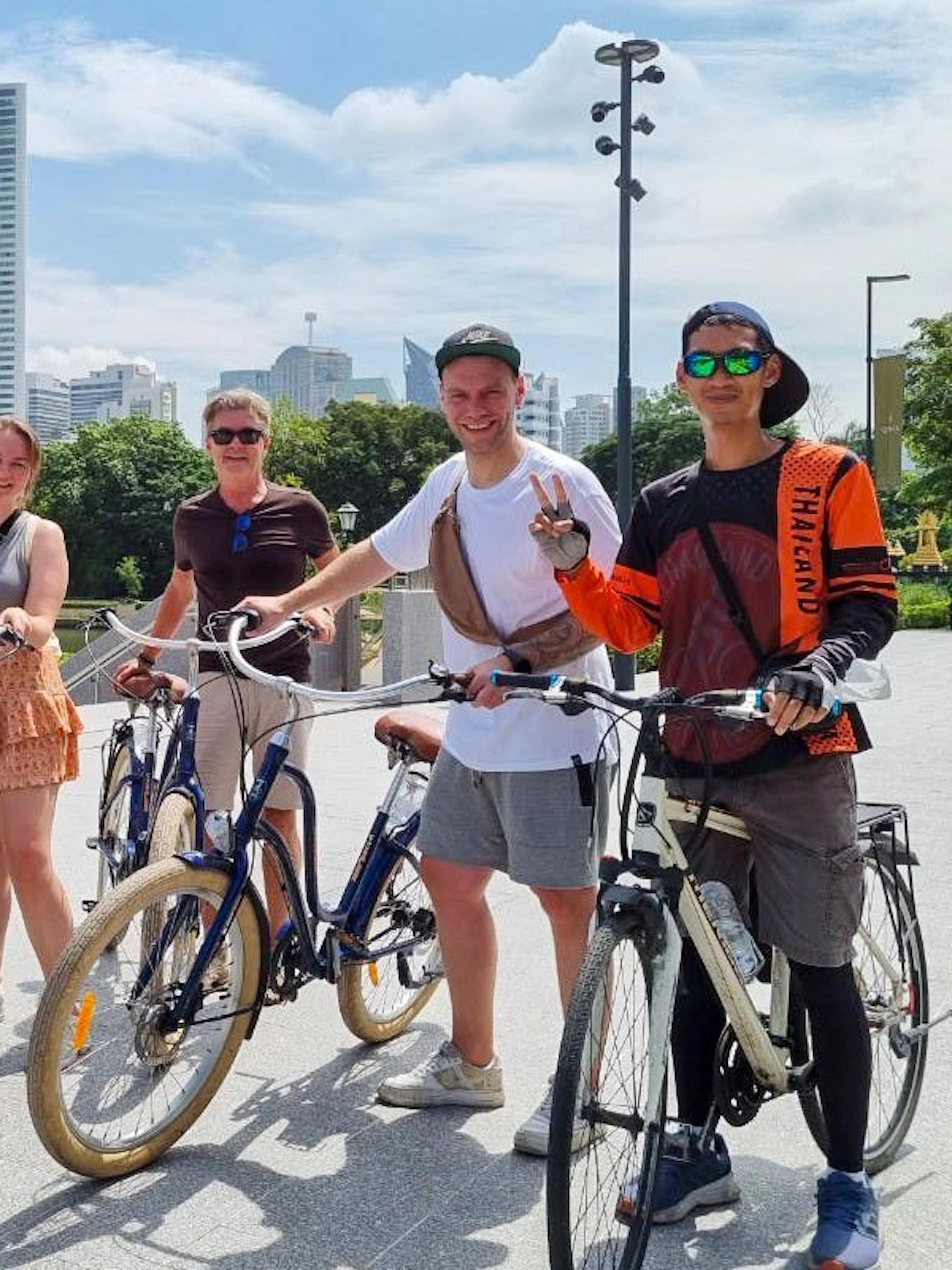 Cyclists on a Bangkok city tour with skyscrapers in the background.