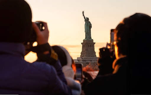 Guests photographing the Statue of Liberty at sunset, New York City.