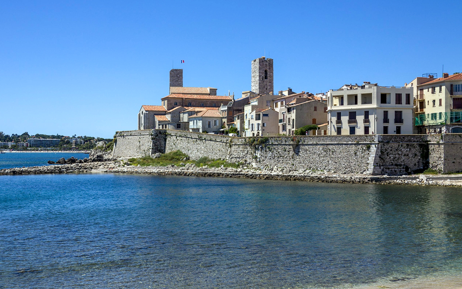 Coastal view of Antibes with historic stone buildings and fortifications by the sea.