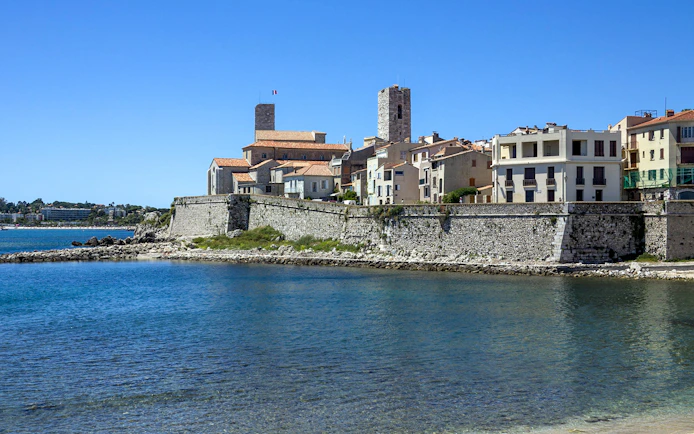 Coastal view of Antibes with historic stone buildings and fortifications by the sea.