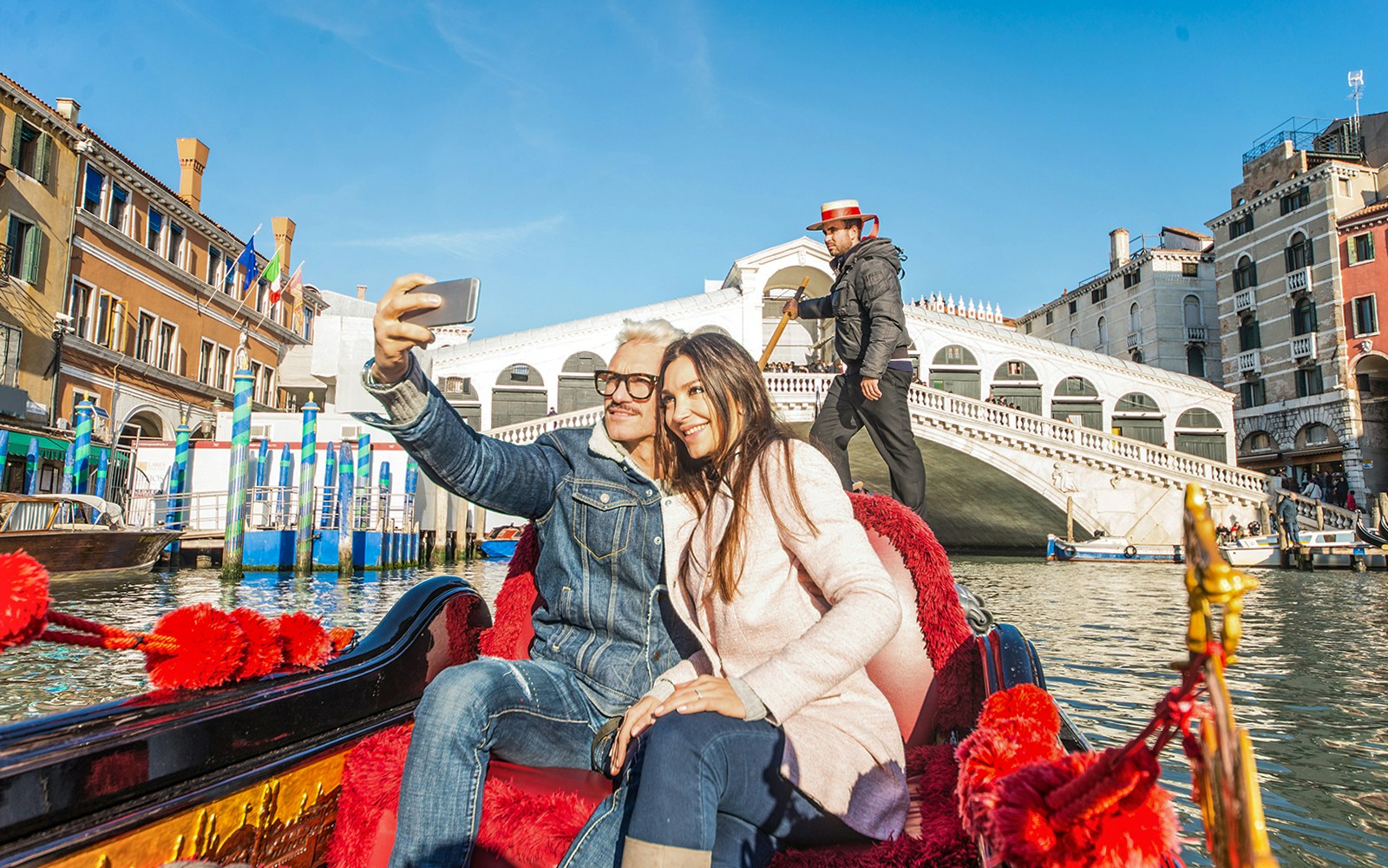 Couple taking selfie on gondola near Rialto Bridge, Venice.