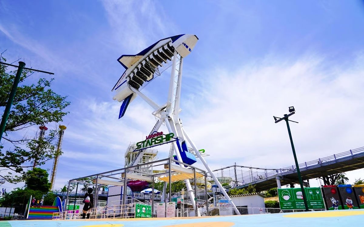 Looping starship ride at Yomiuriland amusement park in Tokyo against a clear sky.