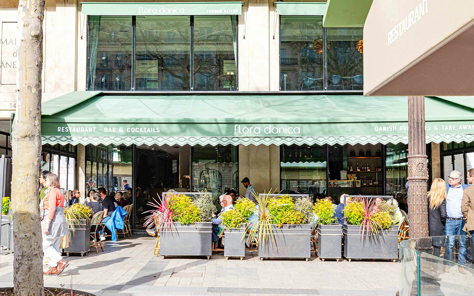 Outdoor seating at Flora Danica on Champs Elysées, Paris, with patrons enjoying brunch.