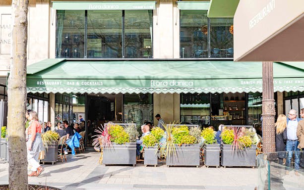 Outdoor seating at Flora Danica on Champs Elysées, Paris, with patrons enjoying brunch.