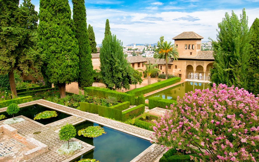 Alhambra's lush gardens with reflecting pools and historic architecture, Andalusia, Spain.