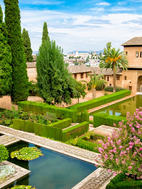 Alhambra's lush gardens with reflecting pools and historic architecture, Andalusia, Spain.