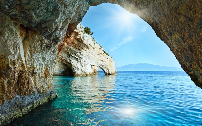 Blue Caves in Zakynthos, Greece with sunlight reflecting on clear turquoise water.