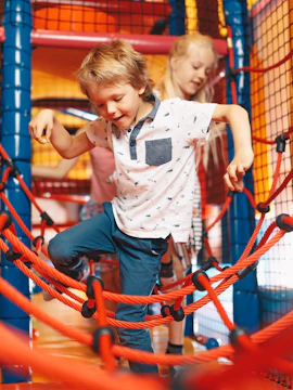Children playing on rope bridge at Waka Waka Indoor Playground.
