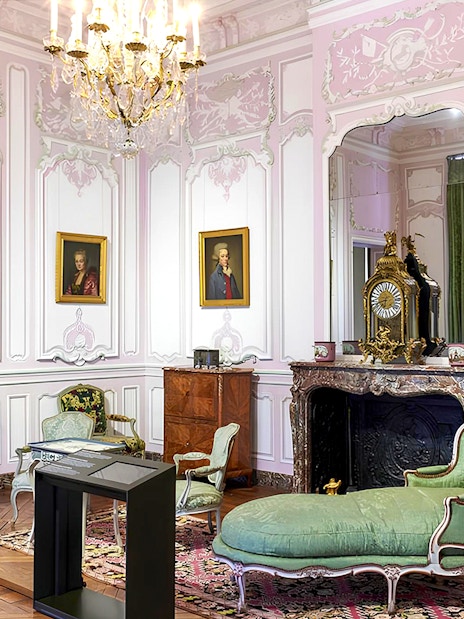 Elegant room in Carnavalet Museum with ornate furniture and historical portraits.