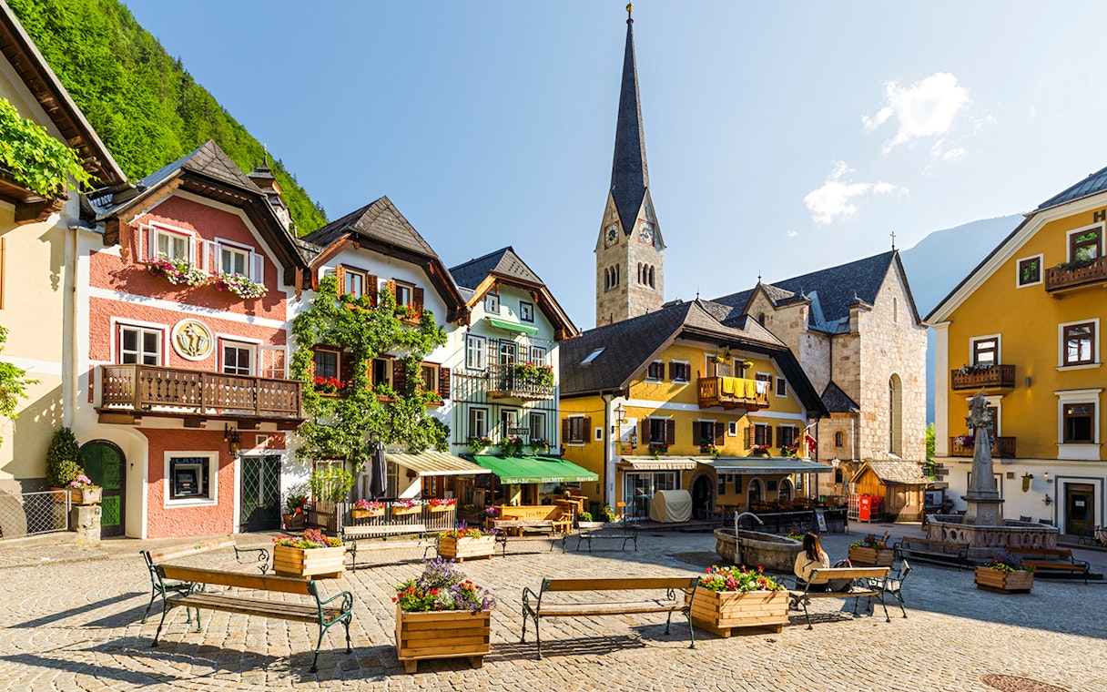 Colourful houses in the old town square of Hallstatt, Austria with a church in the background.