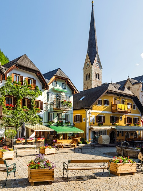 Colourful houses in the old town square of Hallstatt, Austria with a church in the background.