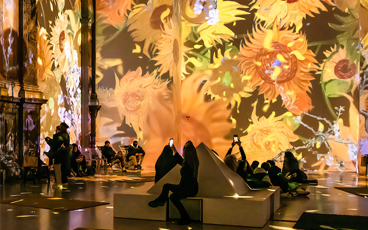 Guests viewing Van Gogh sunflower projections at London exhibition.