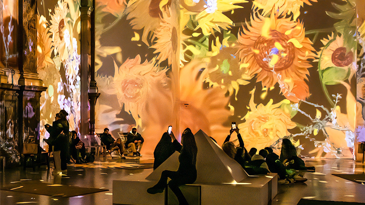 Guests viewing Van Gogh sunflower projections at London exhibition.