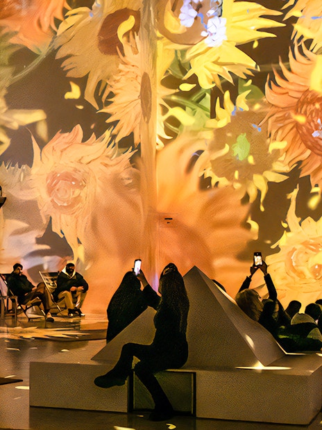Guests viewing Van Gogh sunflower projections at London exhibition.