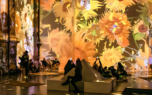 Guests viewing Van Gogh sunflower projections at London exhibition.