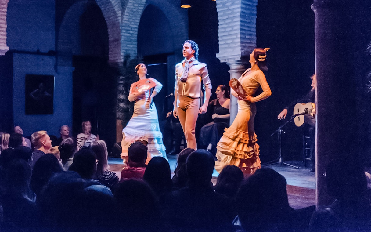 Flamenco dancers performing at Dance Museum with guitarist in background.