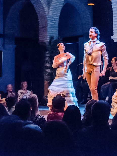 Flamenco dancers performing at Dance Museum with guitarist in background.