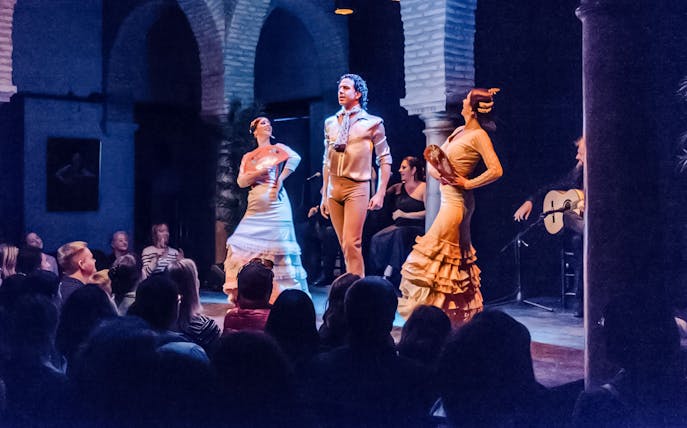 Flamenco dancers performing at Dance Museum with guitarist in background.