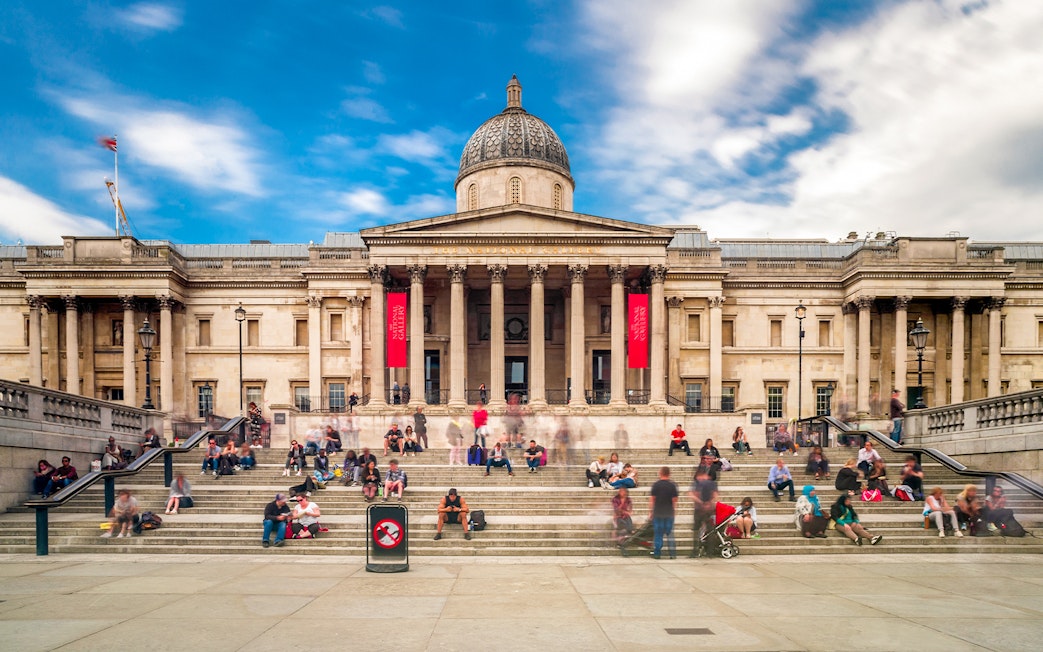 Visitors sitting on steps outside the National Gallery in London.