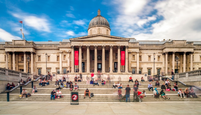 Visitors sitting on steps outside the National Gallery in London.