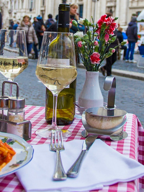 Pasta dishes and wine on a checkered table in Trastevere, Rome.