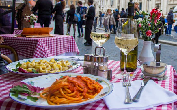 Pasta dishes and wine on a checkered table in Trastevere, Rome.