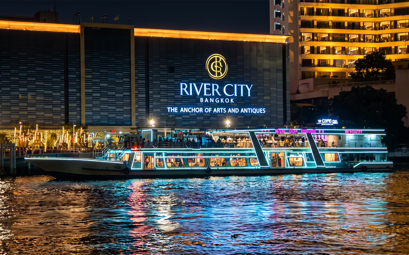 River Star Princess cruise on Chao Phraya River at night, passing River City Bangkok.