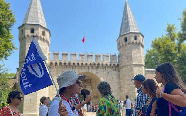 Guided group at Topkapi Palace entrance, Istanbul, with tour flag.