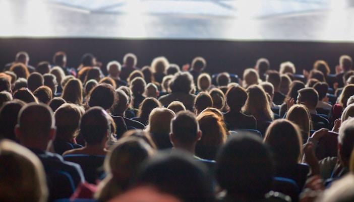 Audience seated in a theater facing the stage.