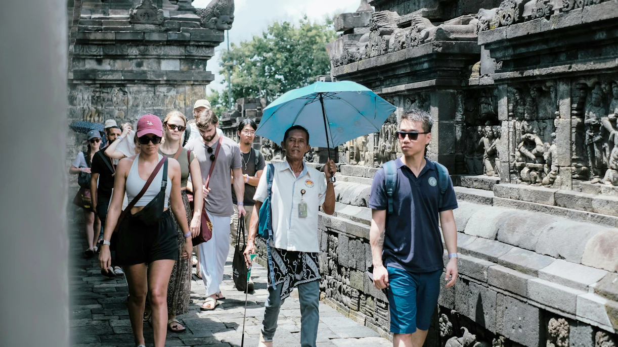 Tourists walking along the stone carvings of Borobudur Temple, Indonesia.