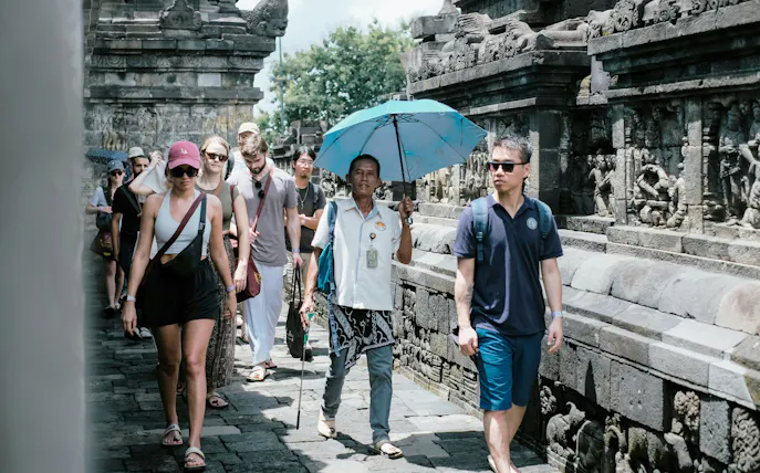 Tourists walking along the stone carvings of Borobudur Temple, Indonesia.