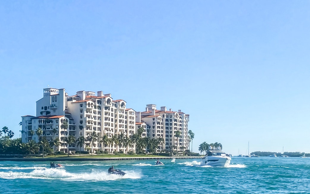 Luxury yacht cruising past waterfront homes in Miami.