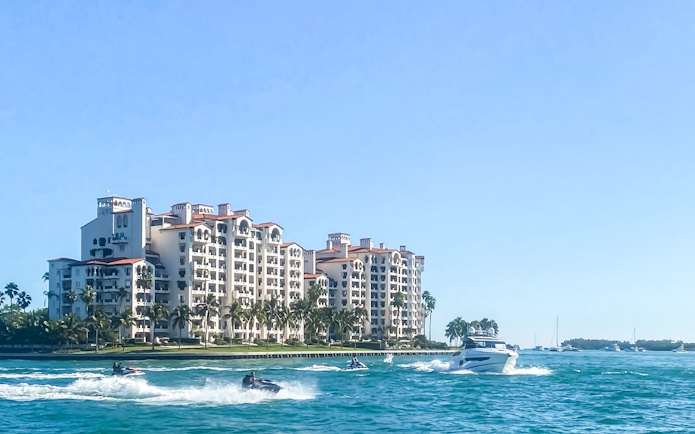Luxury yacht cruising past waterfront homes in Miami.