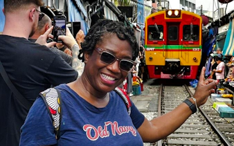 Tourist at Maeklong Railway Market with train approaching, part of Floating Market & Railway Market tour from Laem Chabang, Pattaya.