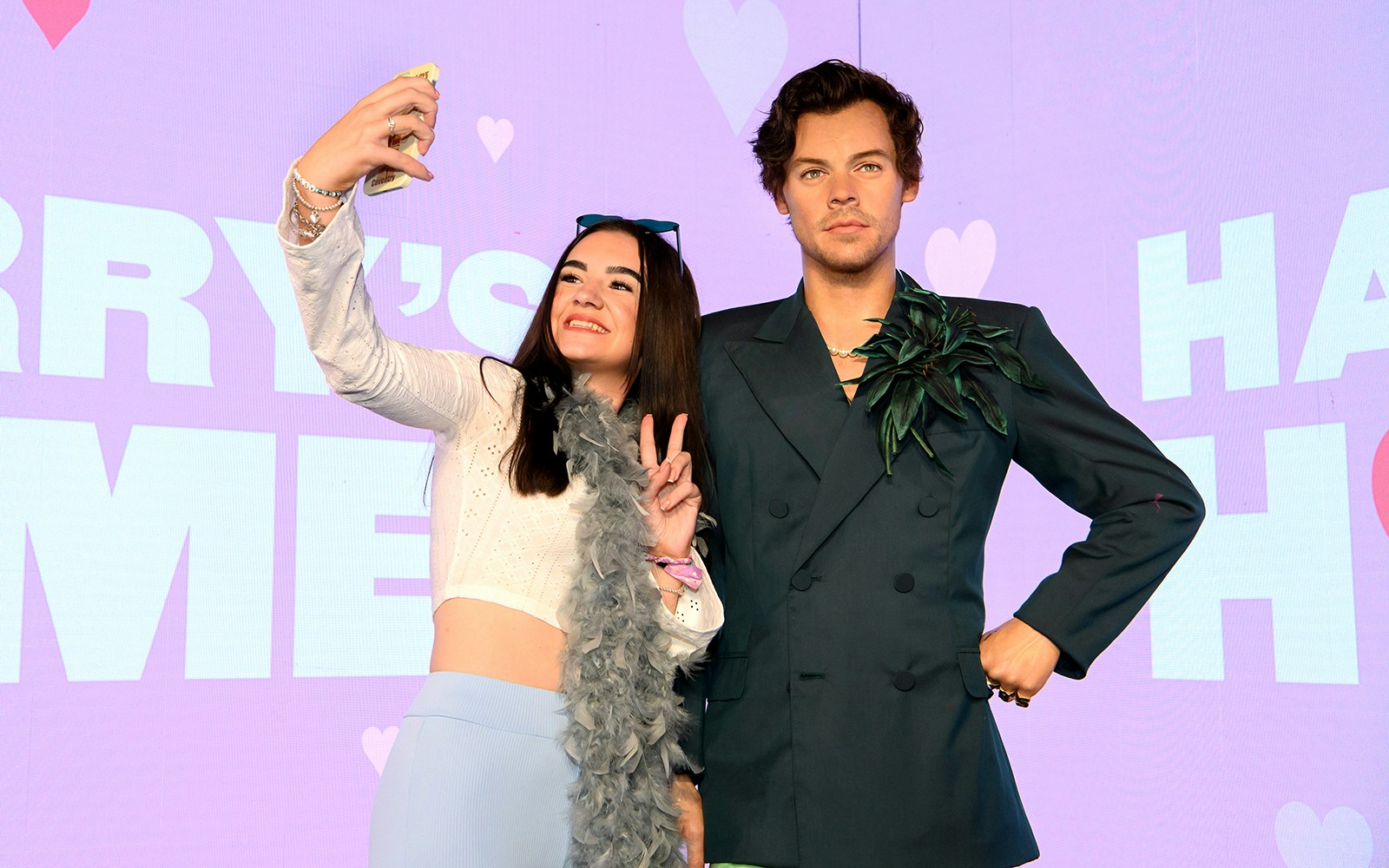 Visitors taking a selfie with Harry Styles wax figure at Madame Tussauds.