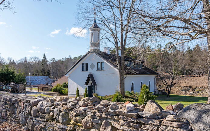 Kelia Joa church in Estonia with stone wall and trees in the background.