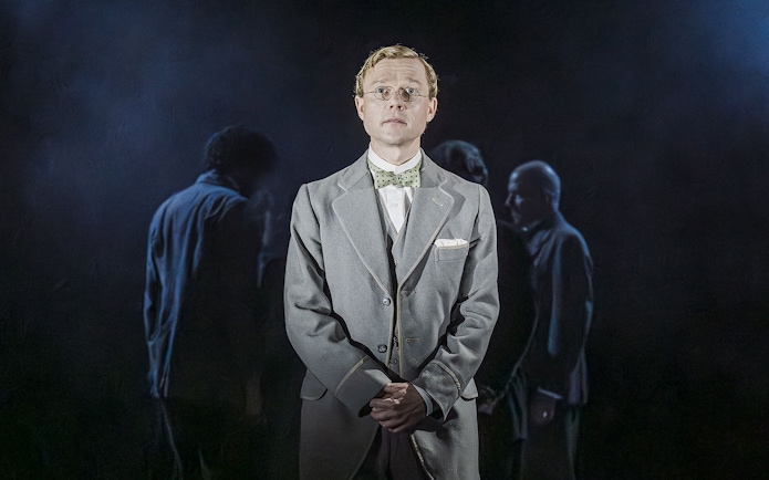 Performer in Grace Pervades West End show with cast in background.